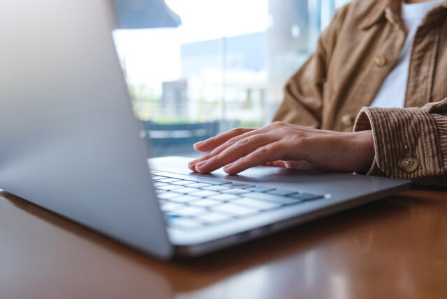 A close up of a person's hand while they work on a laptop.