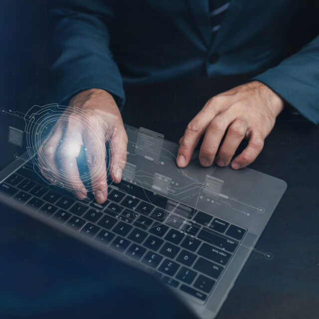 A person in a suit uses a laptop, with digital data graphics overlayed on the image, suggesting cybersecurity or data analysis.