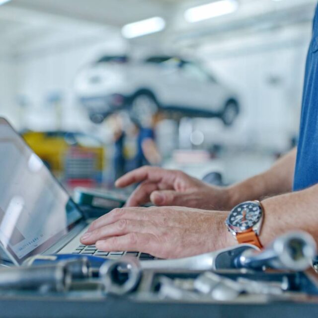 Man working on laptop at auto repair garage