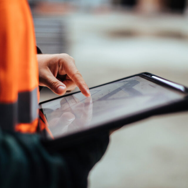 Unrecognizable construction worker hands holding a digital tablet while working outdoors