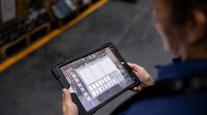 Close-up on a warehouse worker using a digital tablet while searching for merchandise