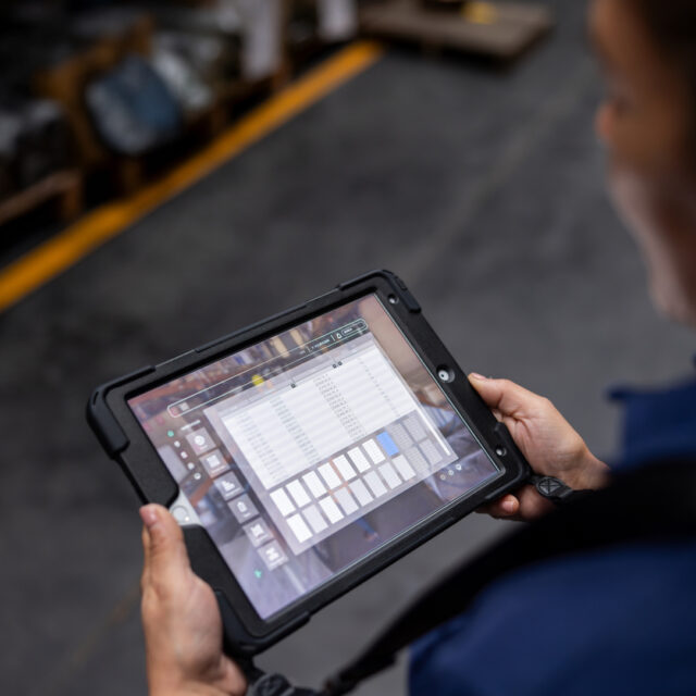 Close-up on a warehouse worker using a digital tablet while searching for merchandise