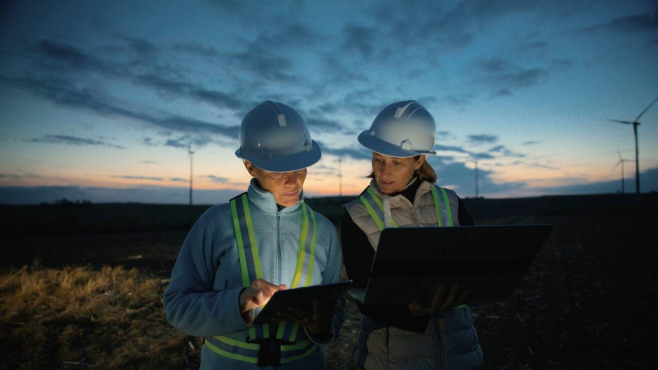 Two workers looking at a tablet at night