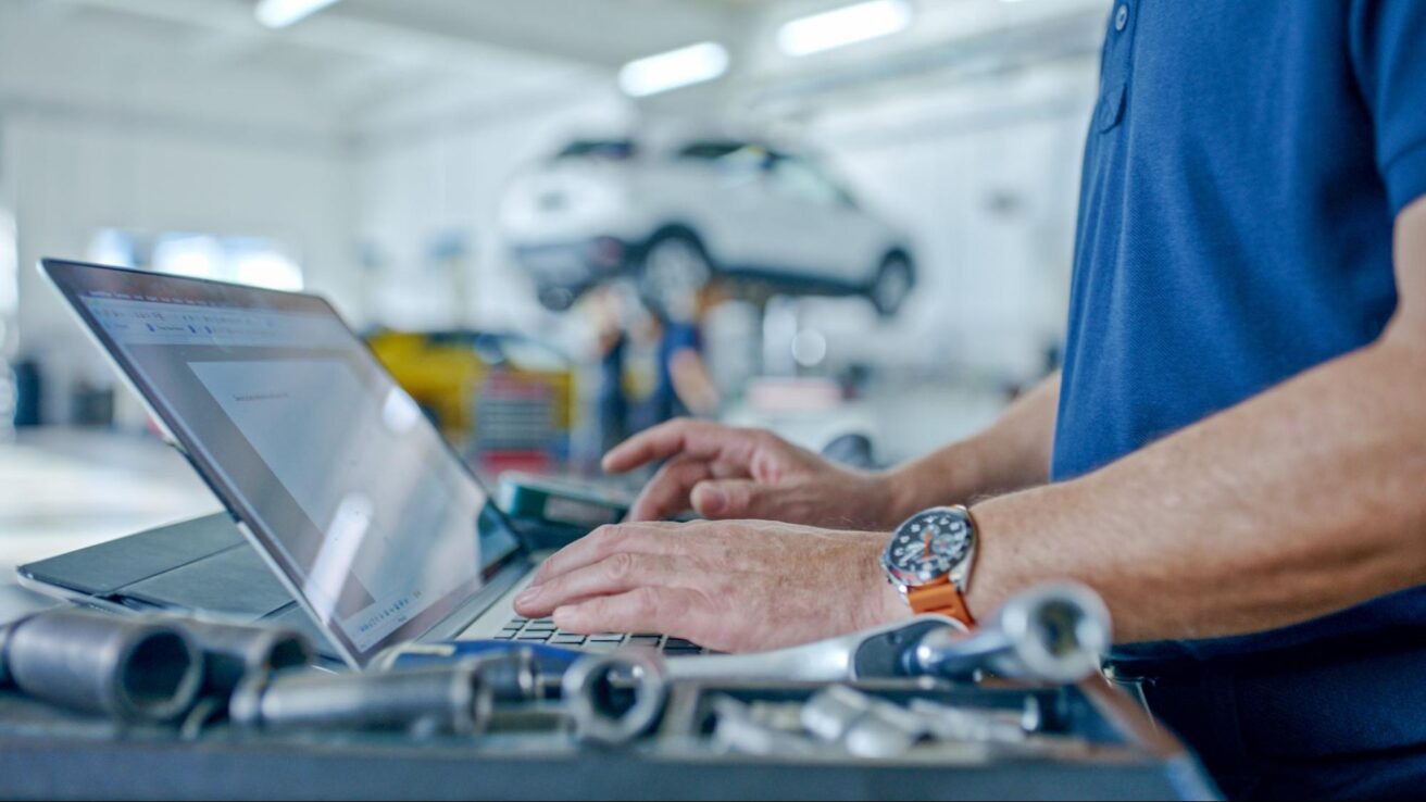 Man working on laptop at auto repair garage